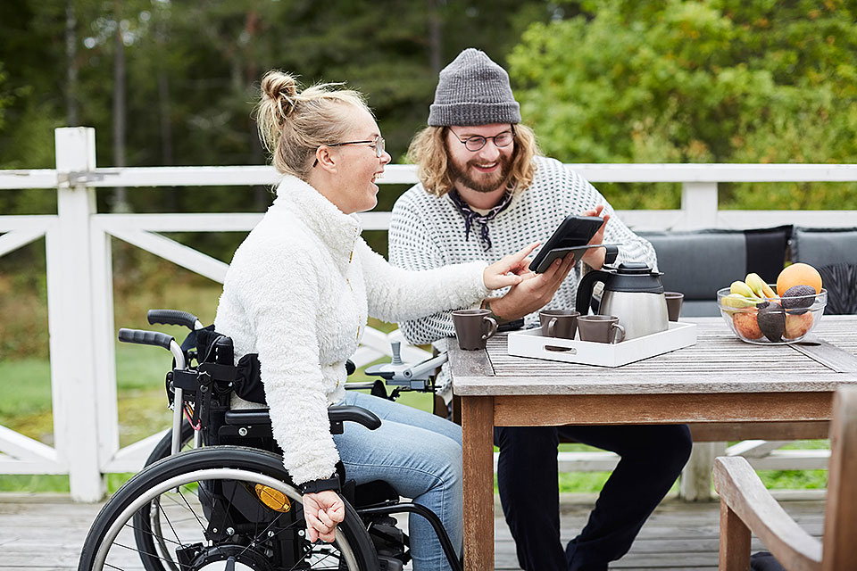 woman in wheelchair and man looking at a tablet